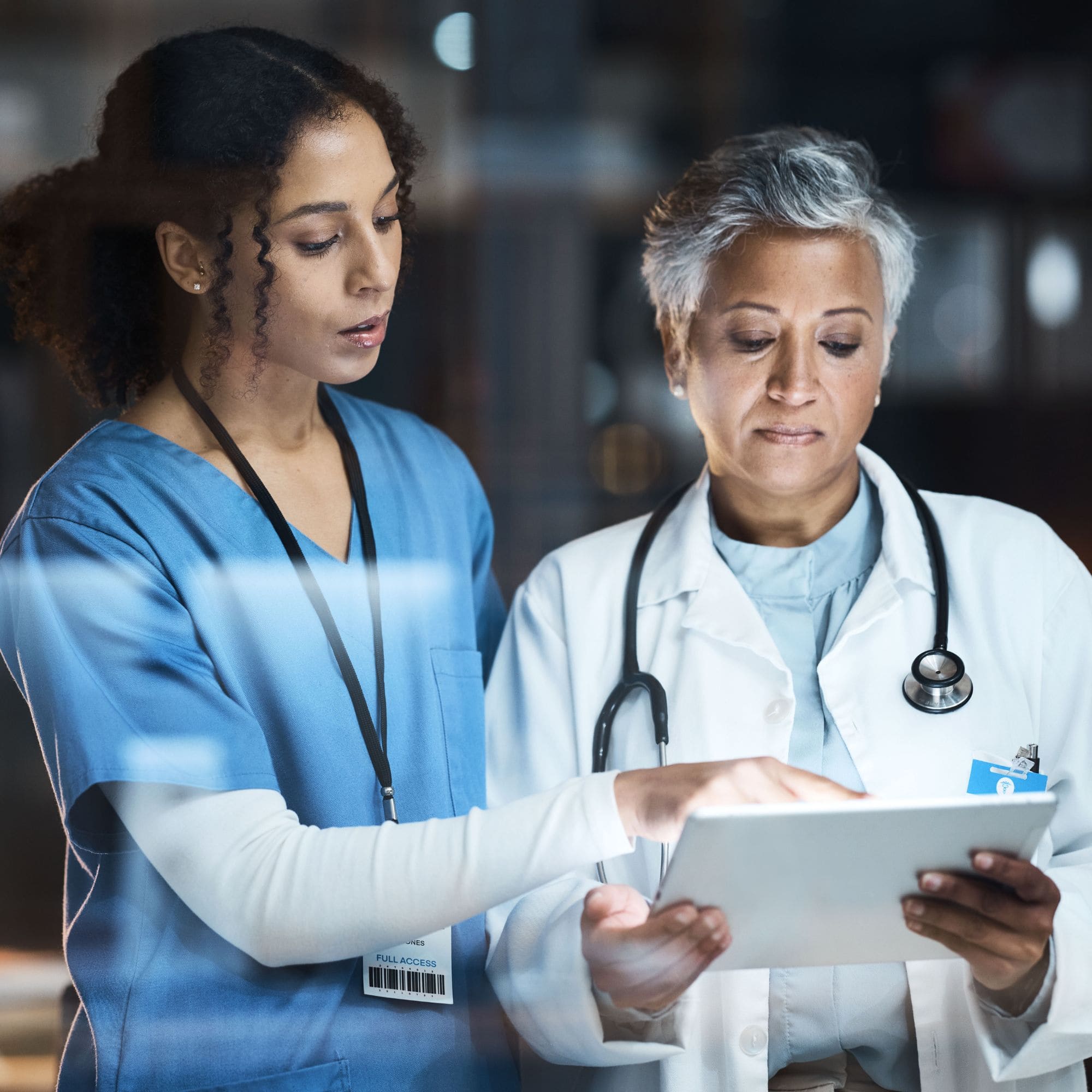 Female nurse looking at tablet with female doctor