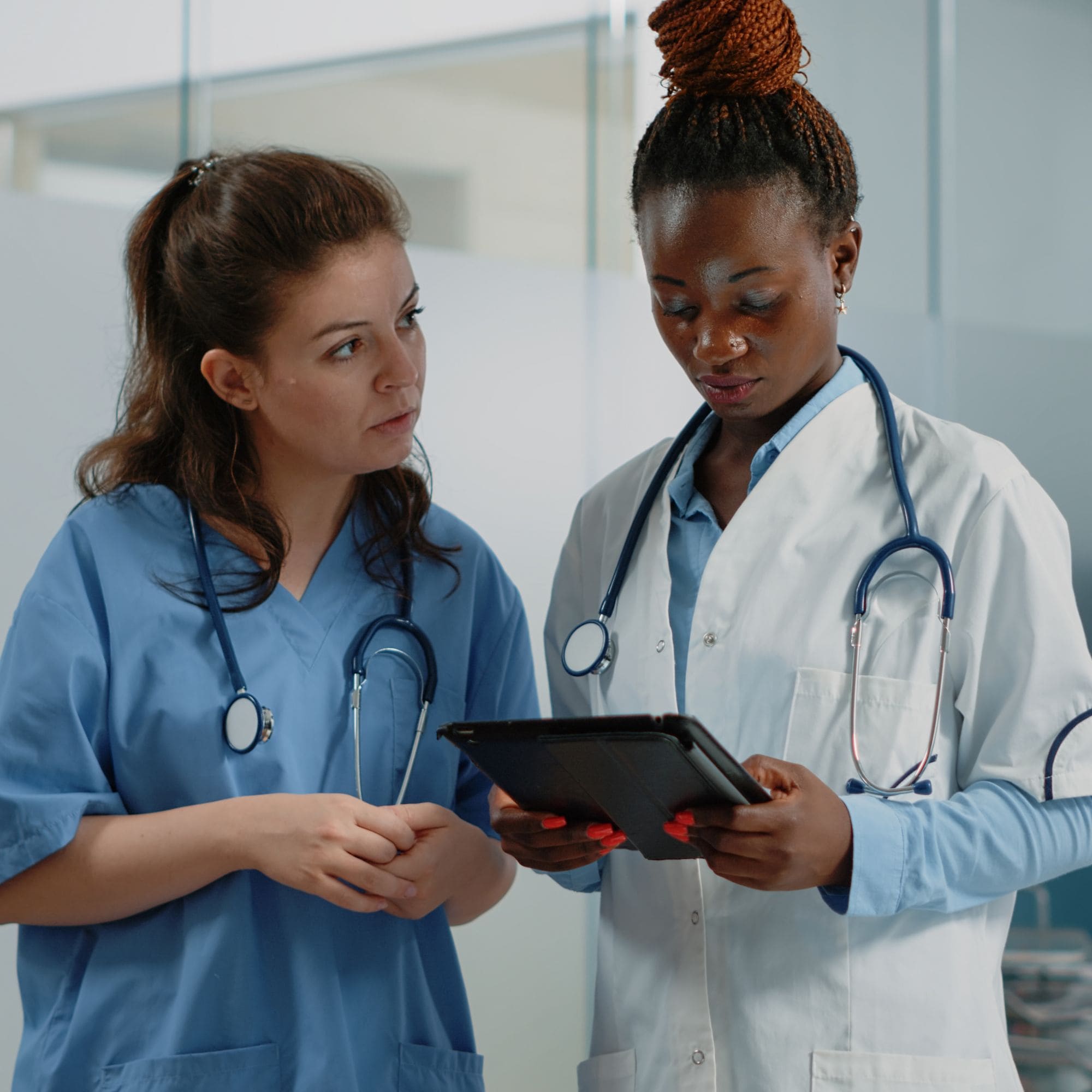 Female nurse and female doctor looking at tablet